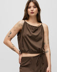 Woman wearing a brown sleeveless top and wide-leg pants on a white background
